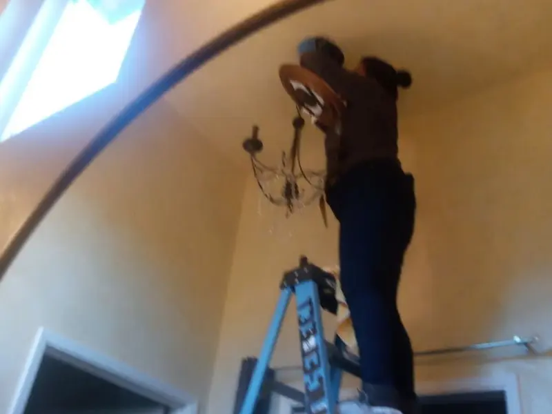 Electrician installing a chandelier in a Port Orange residence